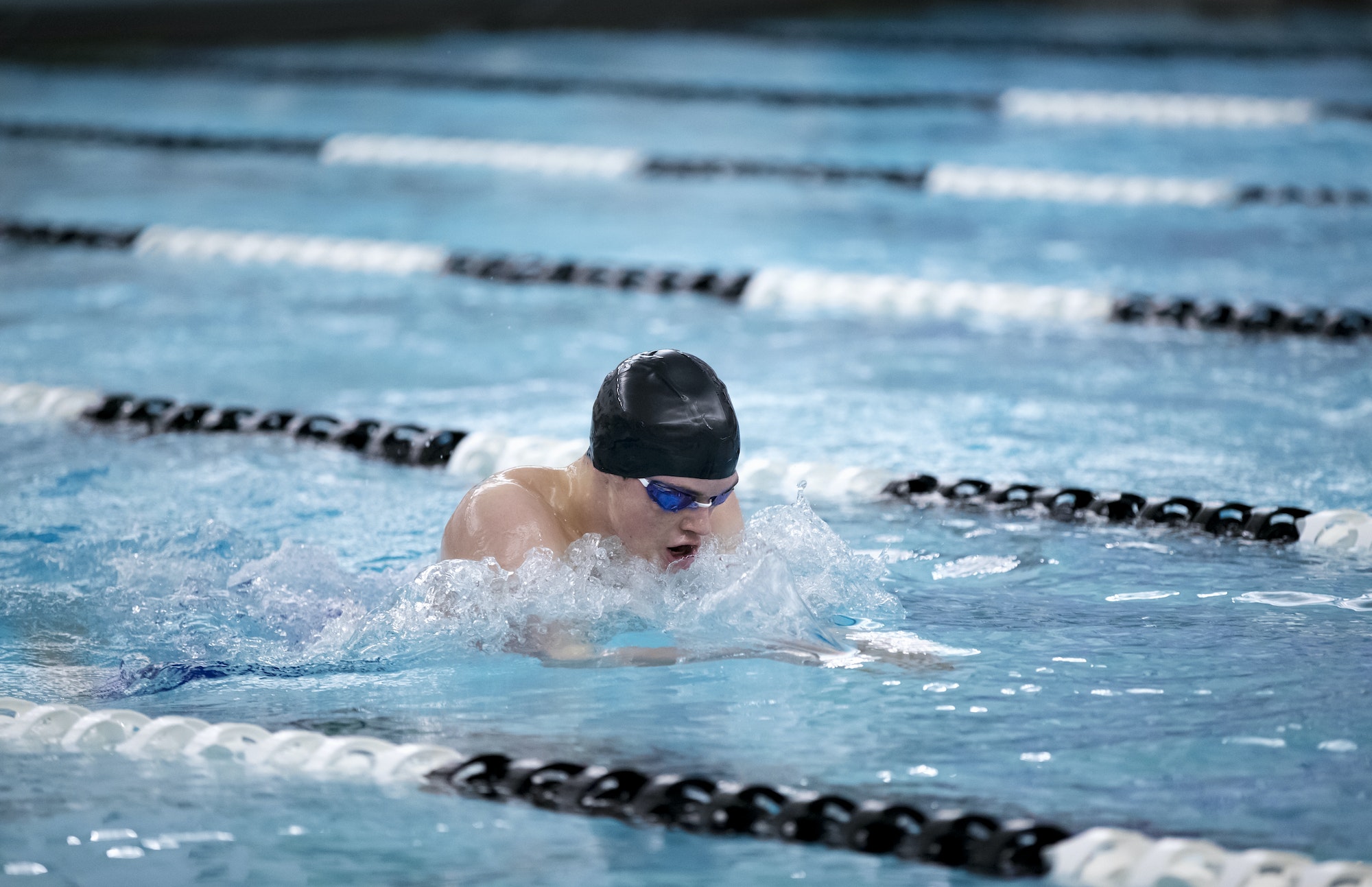 Young male swimmer swims the breaststroke in a pool during a swim meet